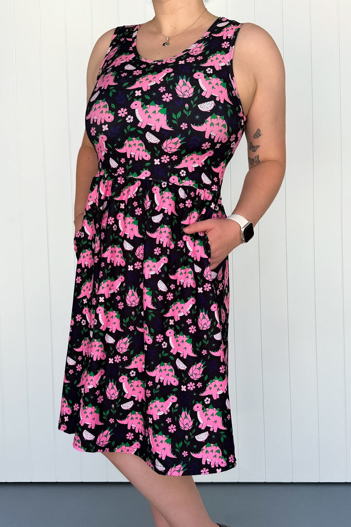 Person wearing a sleeveless dress with pink dinosaur pattern against a white background