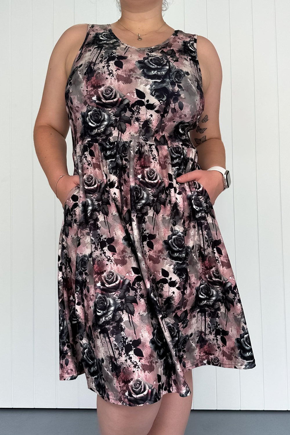 A sleeveless knee-length dress with side pockets featuring a floral pattern with dark, dramatic blooms and ink-splatter textures.