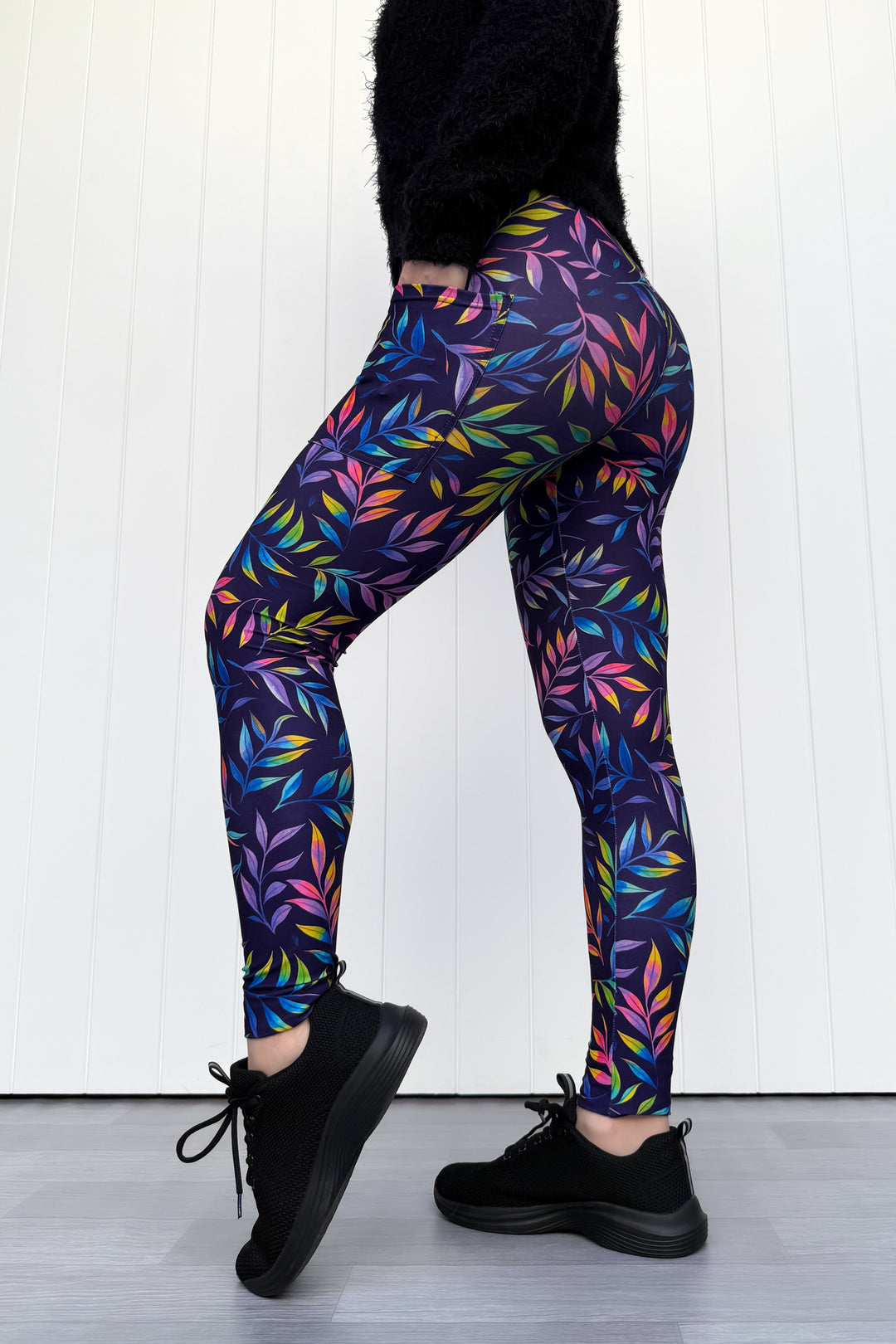 Person wearing colorful leaf-patterned leggings against a white background