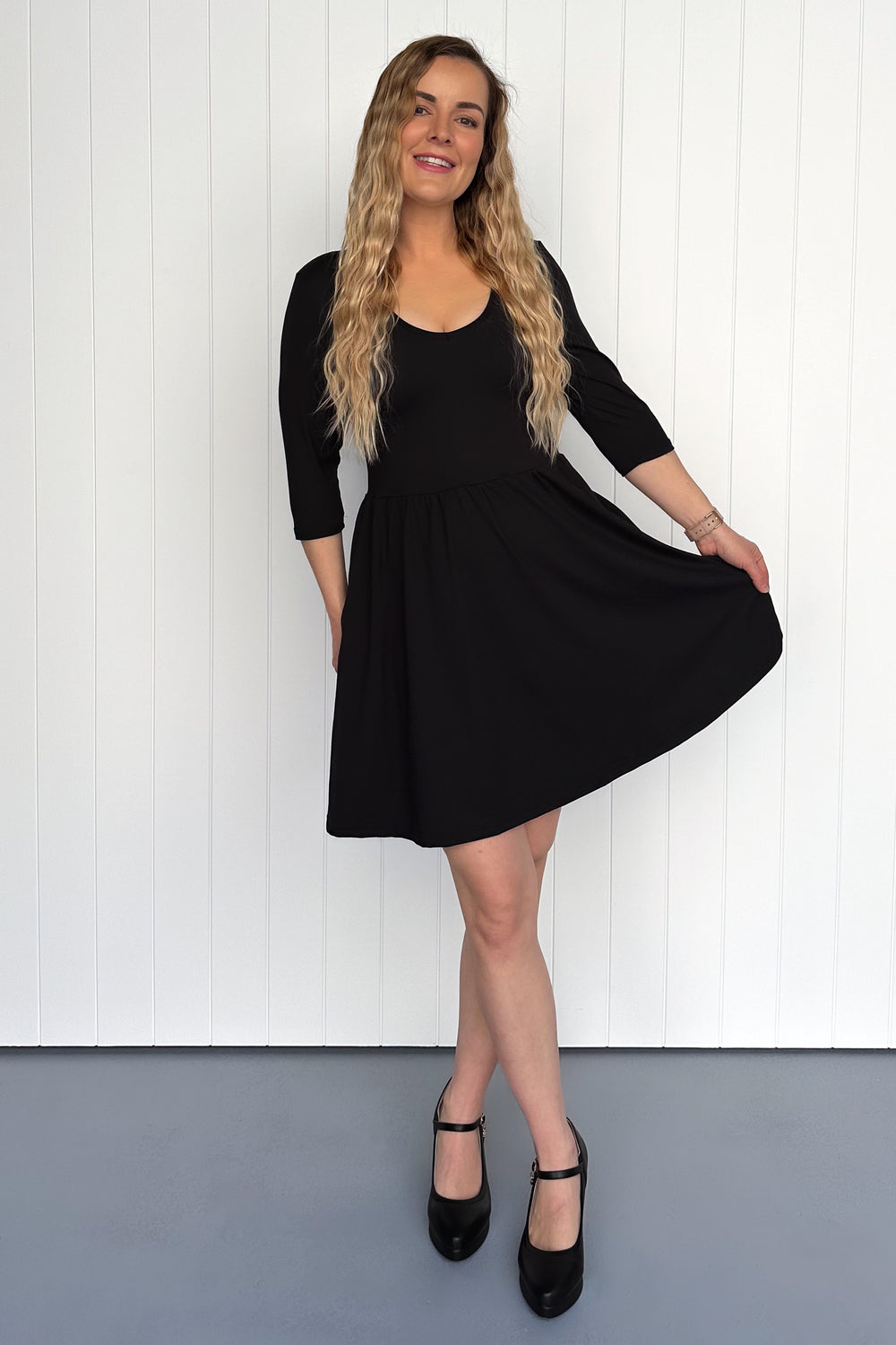 Woman wearing a black dress against a white wall