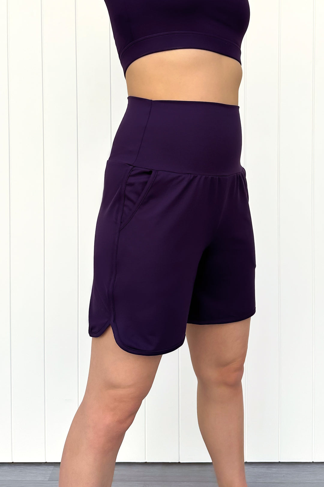 Person wearing purple athletic shorts and top on a white background