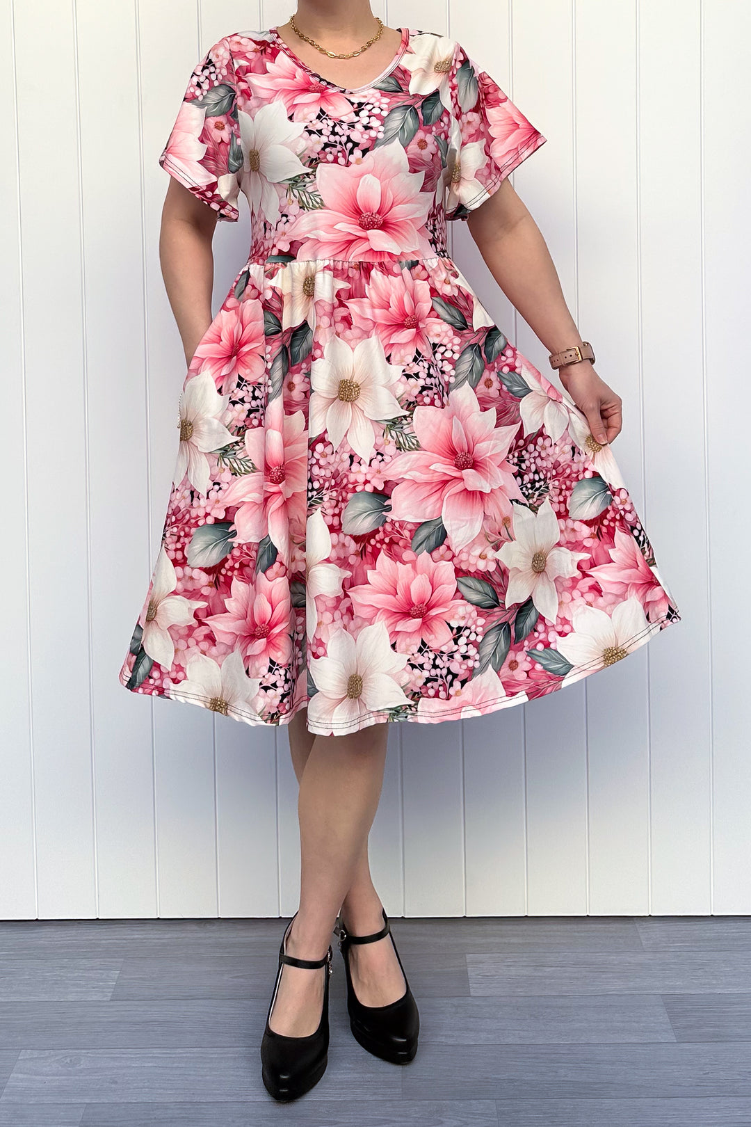 Person wearing a pink and cream floral dress standing in front of white background