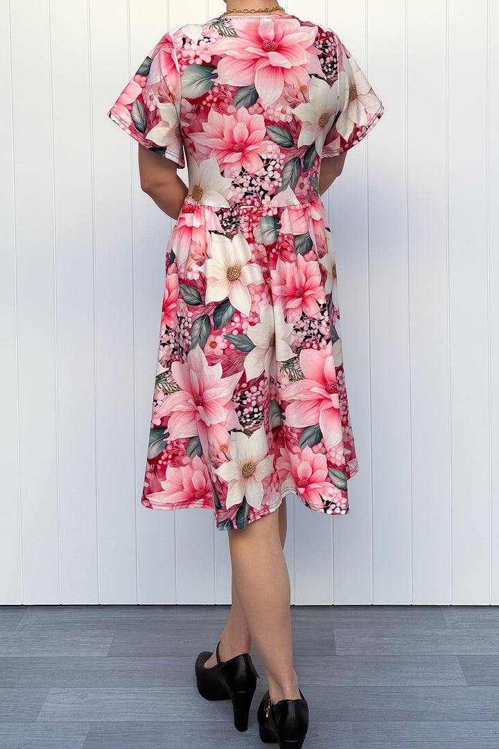 Person wearing a pink and cream floral dress standing in front of white background