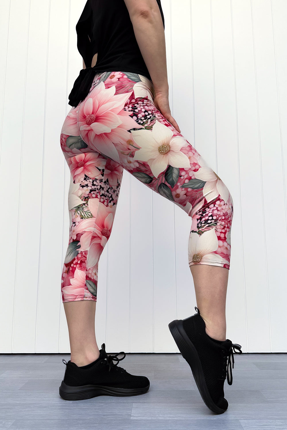 Person wearing pink and cream floral capri leggings standing in front of white background