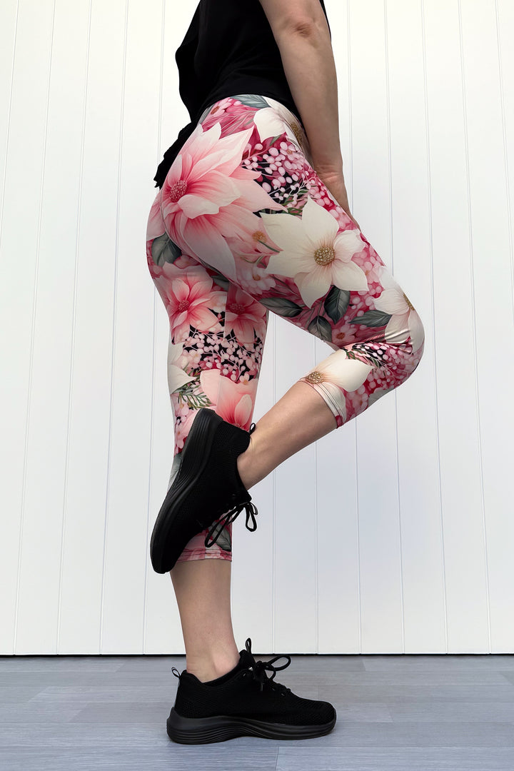 Person wearing pink and cream floral capri leggings standing in front of white background