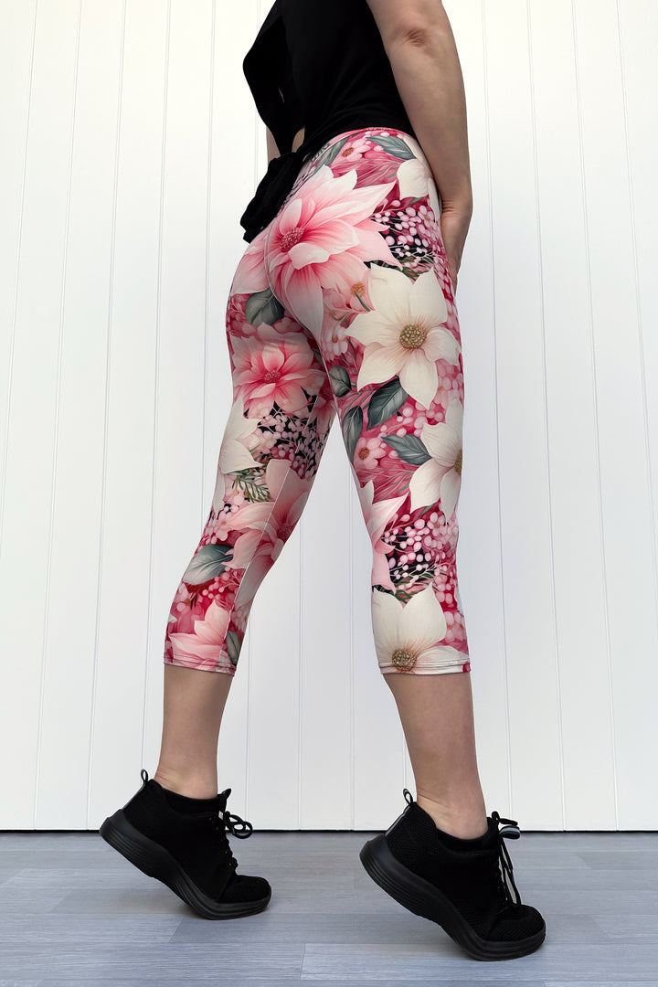Person wearing pink and cream floral capri leggings standing in front of white background