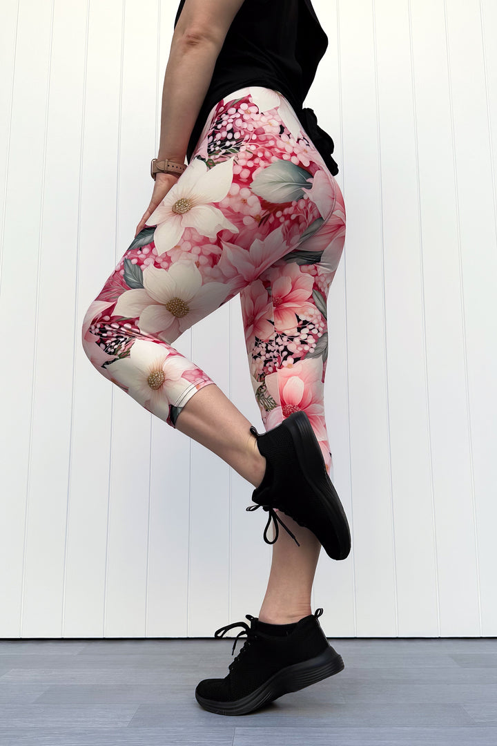 Person wearing pink and cream floral capri leggings standing in front of white background