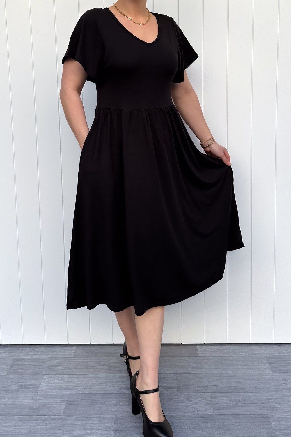 Person wearing a black dress against a white wall