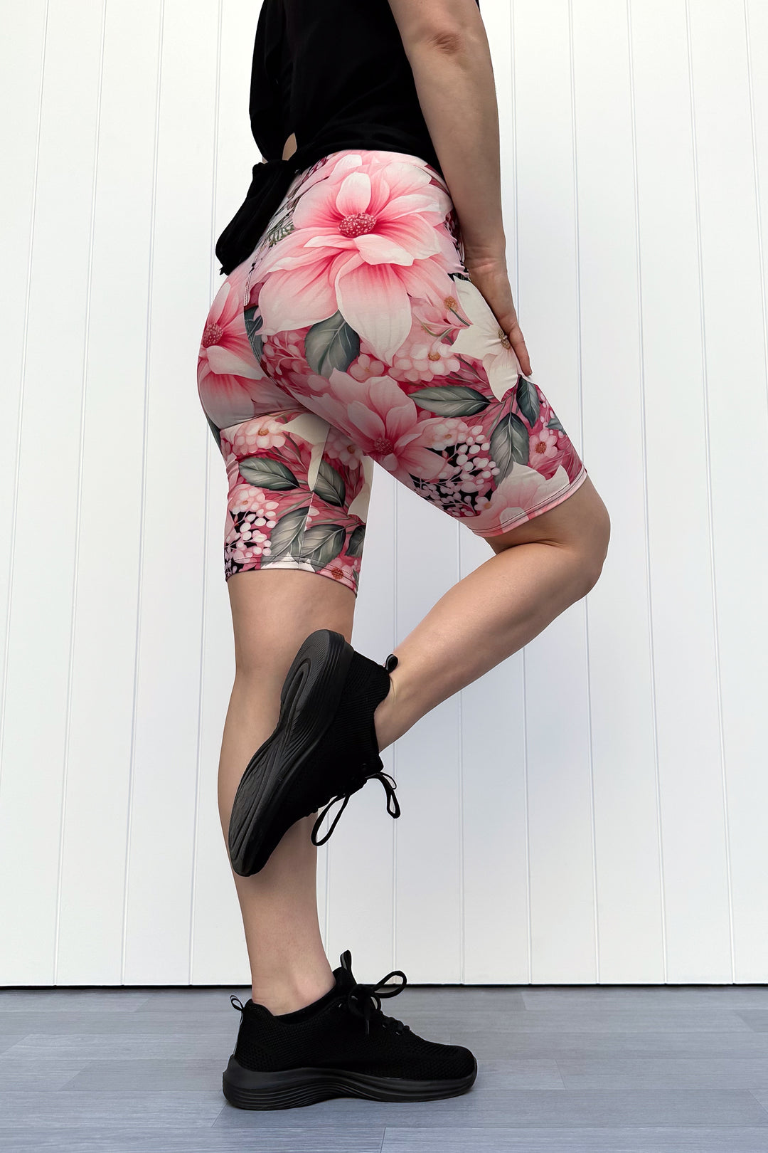 Person wearing pink and cream floral shorts standing in front of white background