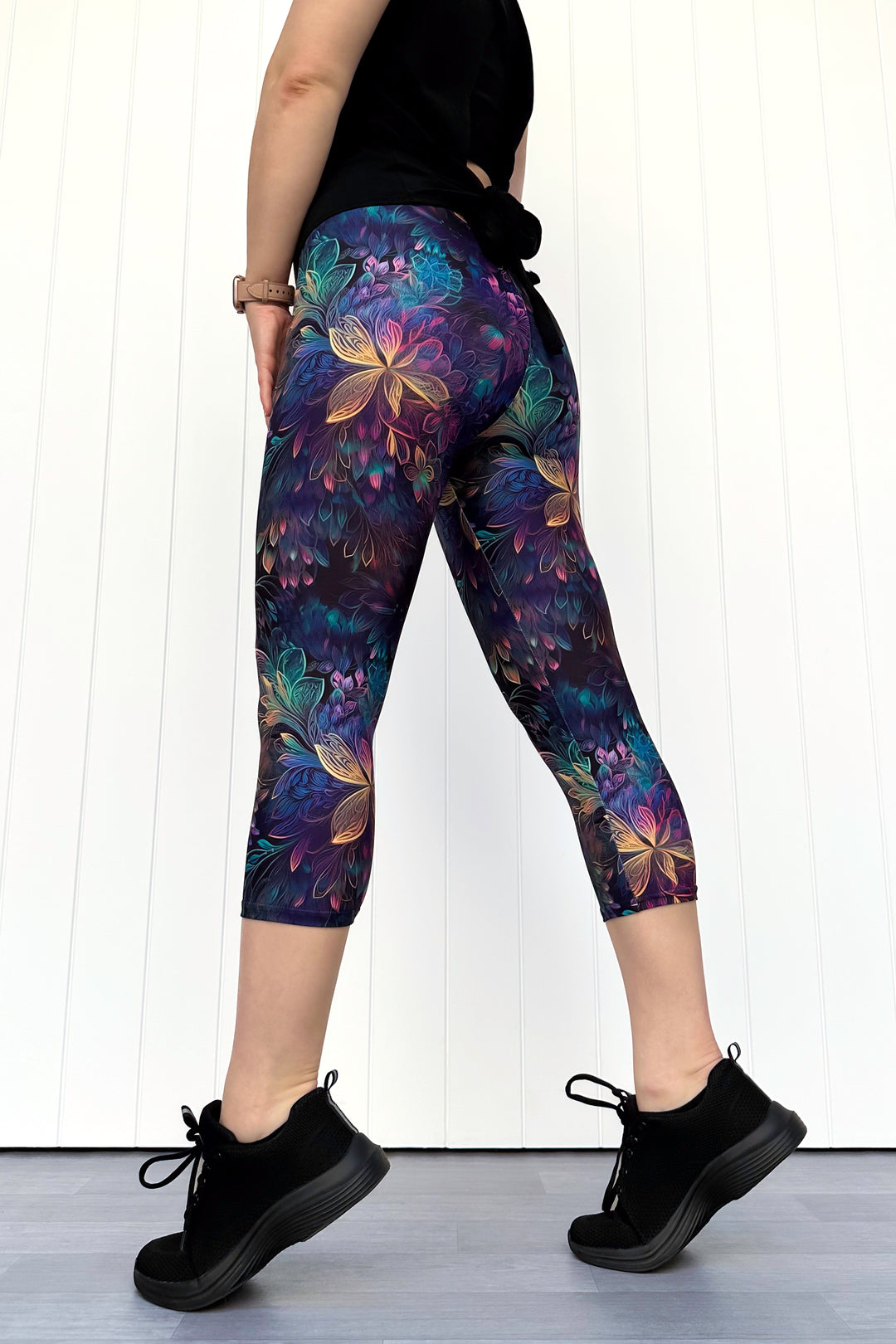 Person wearing colorful floral leggings with a white background