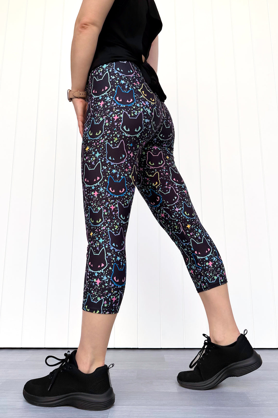 Person wearing black leggings with cat pattern on a white background
