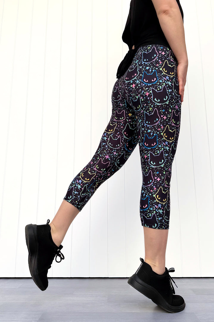 Person wearing black leggings with cat pattern against a white background