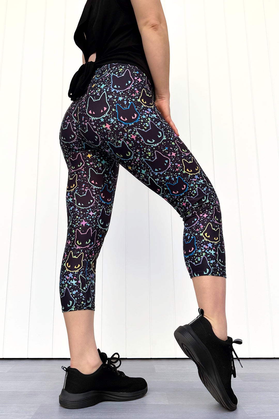 Person wearing black leggings with cat pattern on a white background