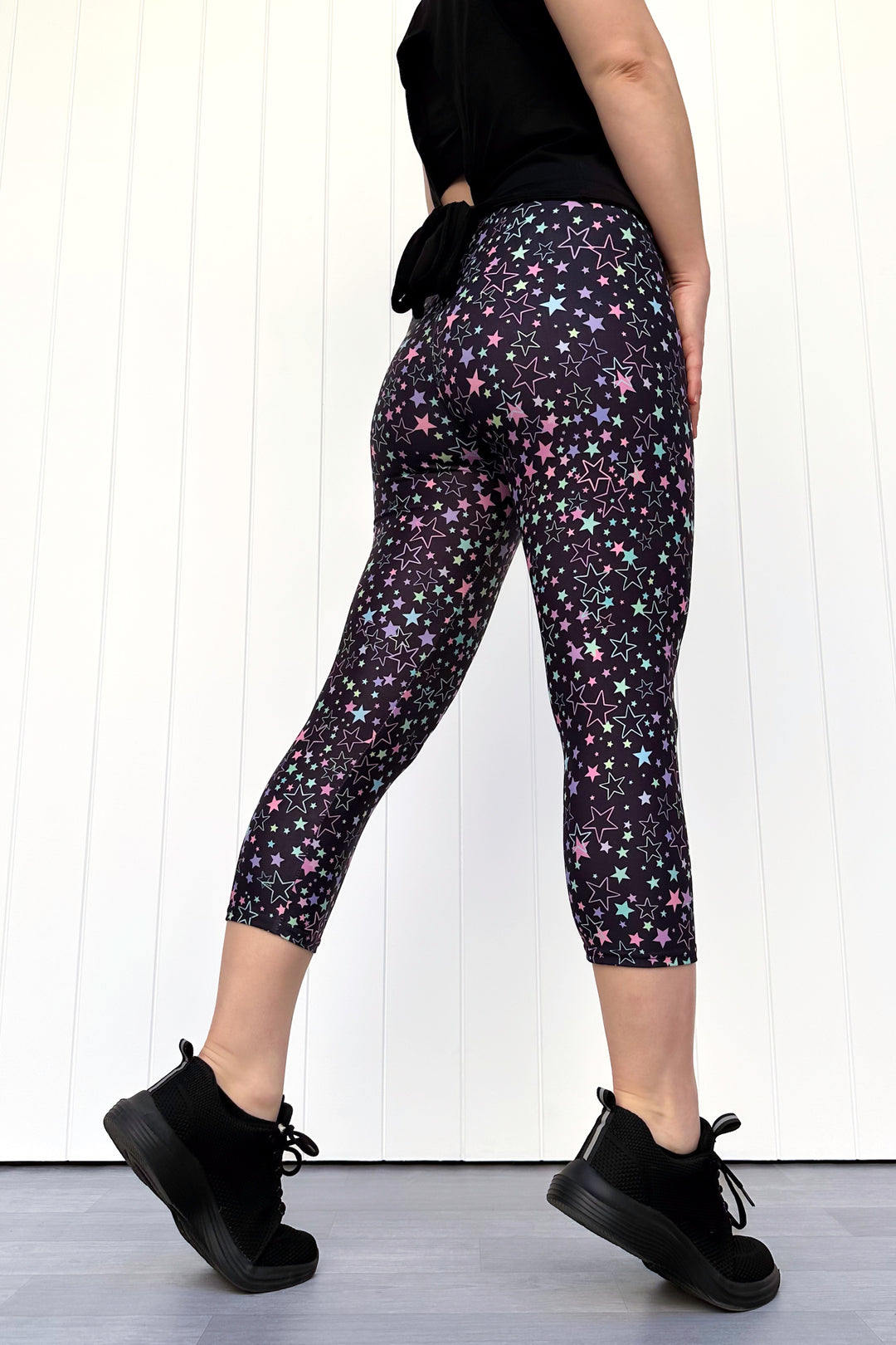 Person wearing black leggings with star pattern against a white background
