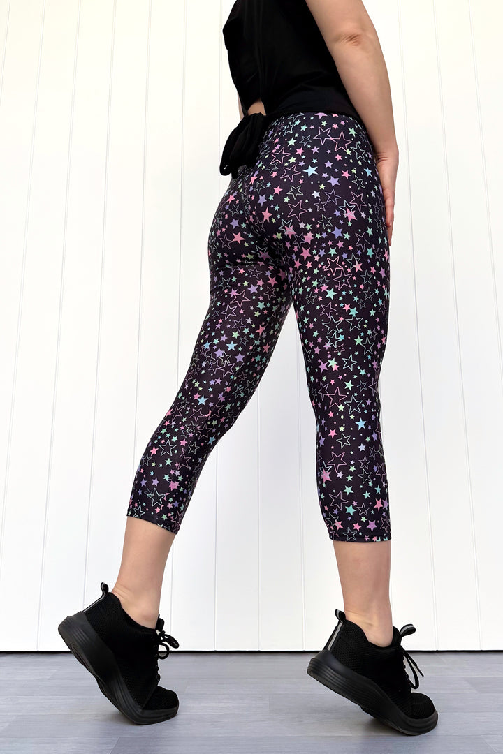 Person wearing black leggings with star pattern against a white background
