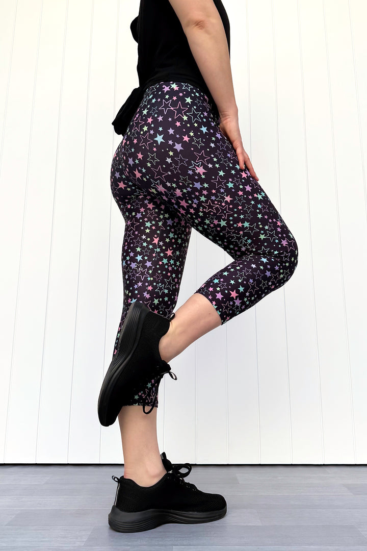 Person wearing black star-patterned leggings with a white background