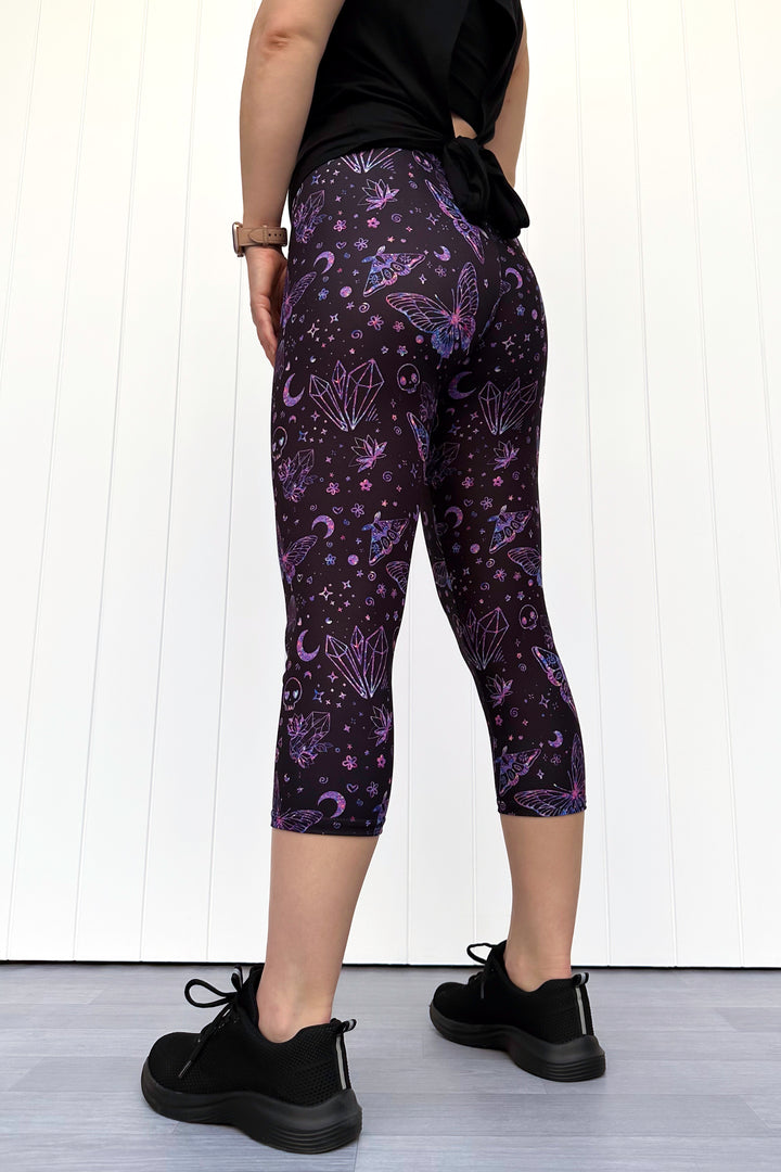 Person wearing purple capri leggings with a celestial pattern against a white background