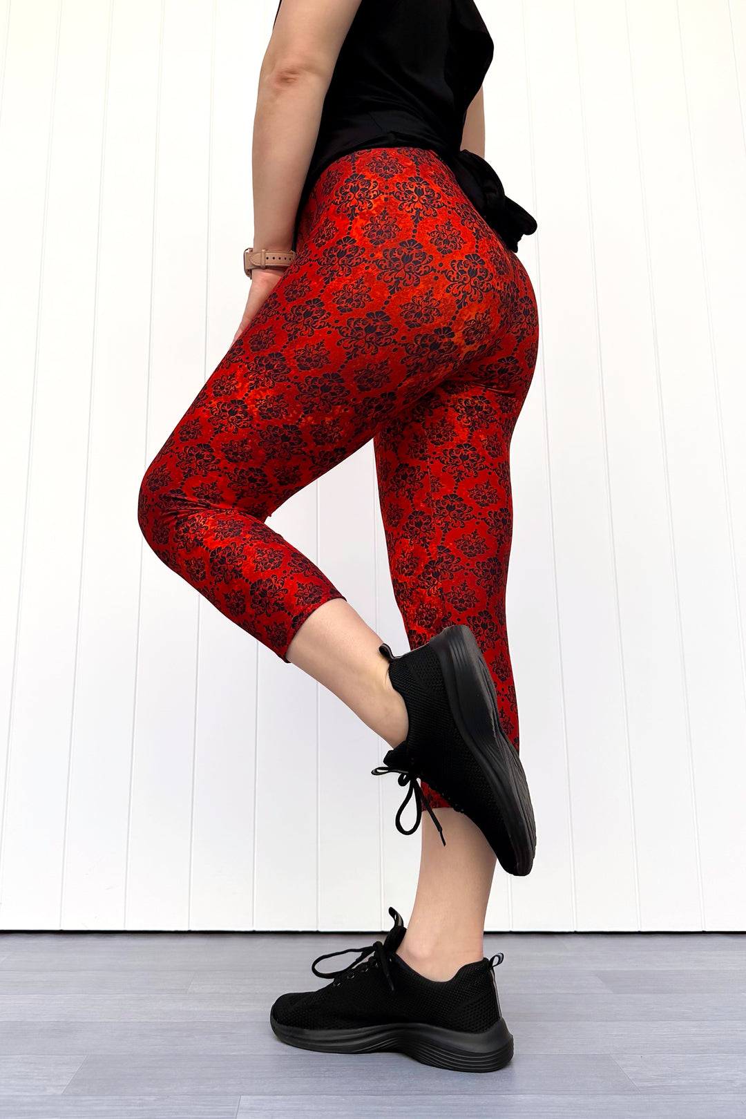Person wearing orange patterned leggings and black shoes on a white background