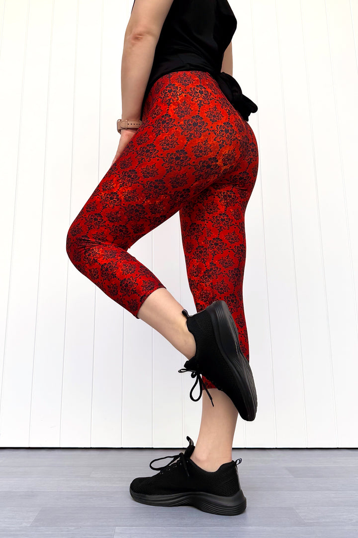 Person wearing orange patterned leggings and black shoes on a white background