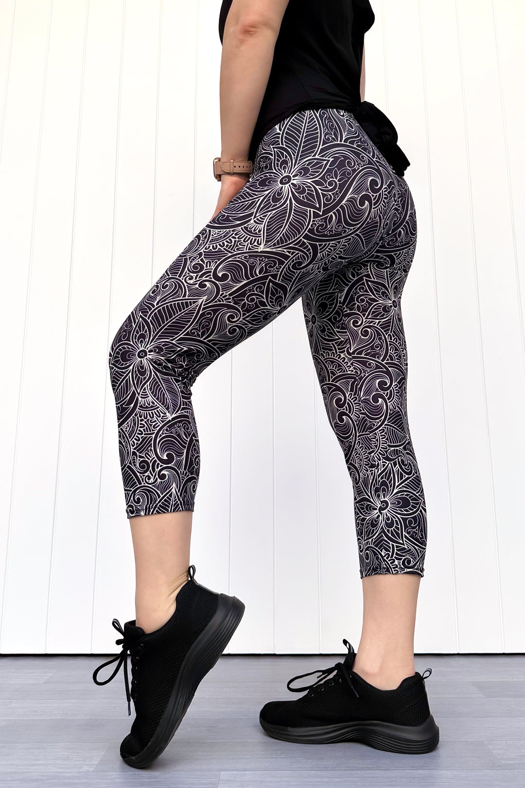 Person wearing black and white patterned leggings with a plain background