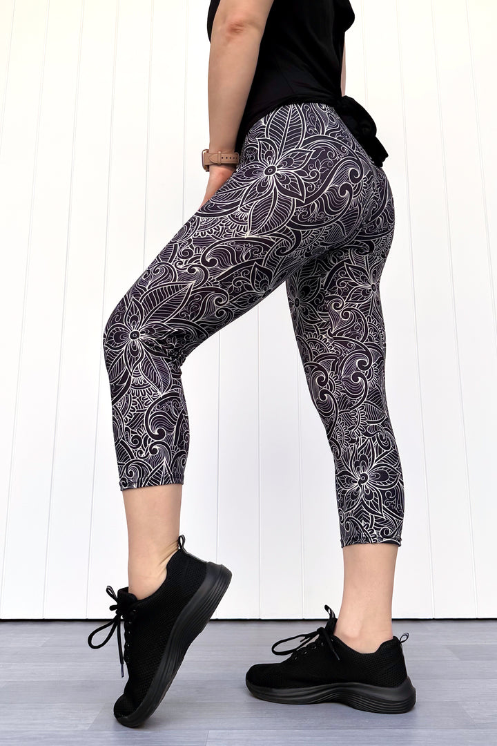 Person wearing black and white patterned leggings with a plain background