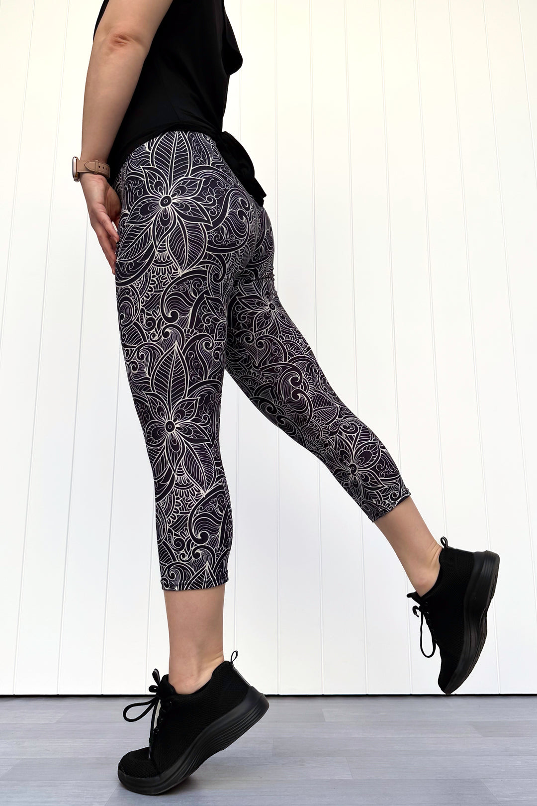 Person wearing black and white patterned leggings with black shoes on a white background