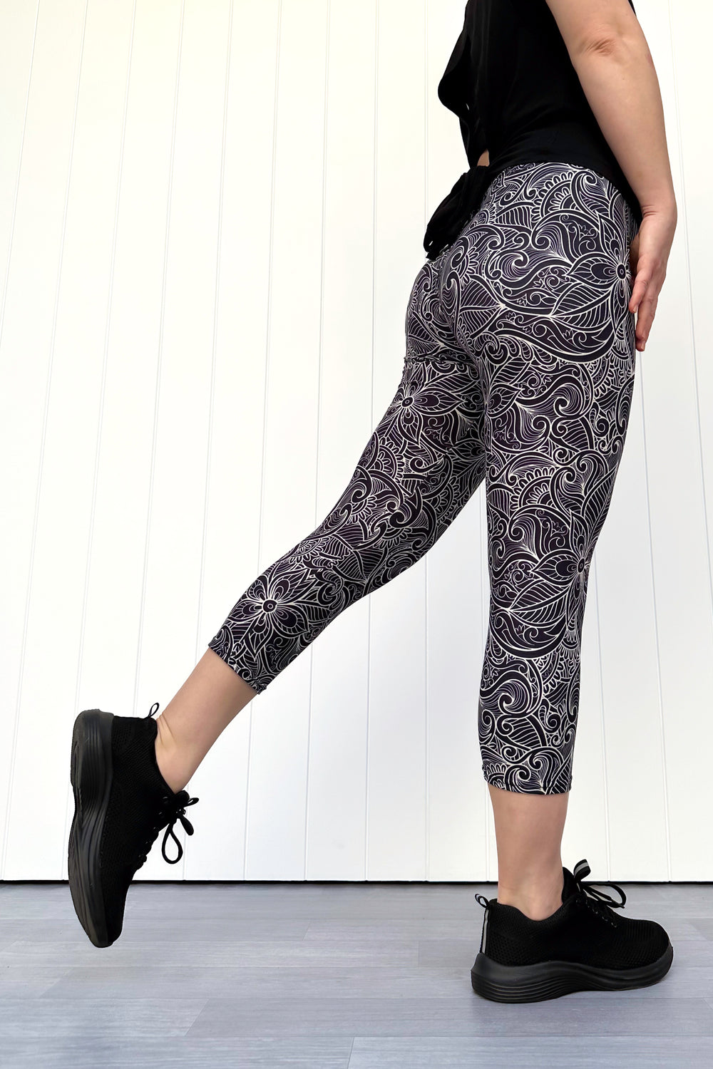 Person wearing black and white patterned leggings with a plain background