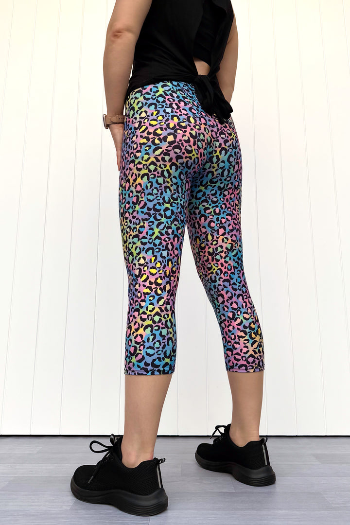 Person wearing colorful leopard print capri pants with a plain background