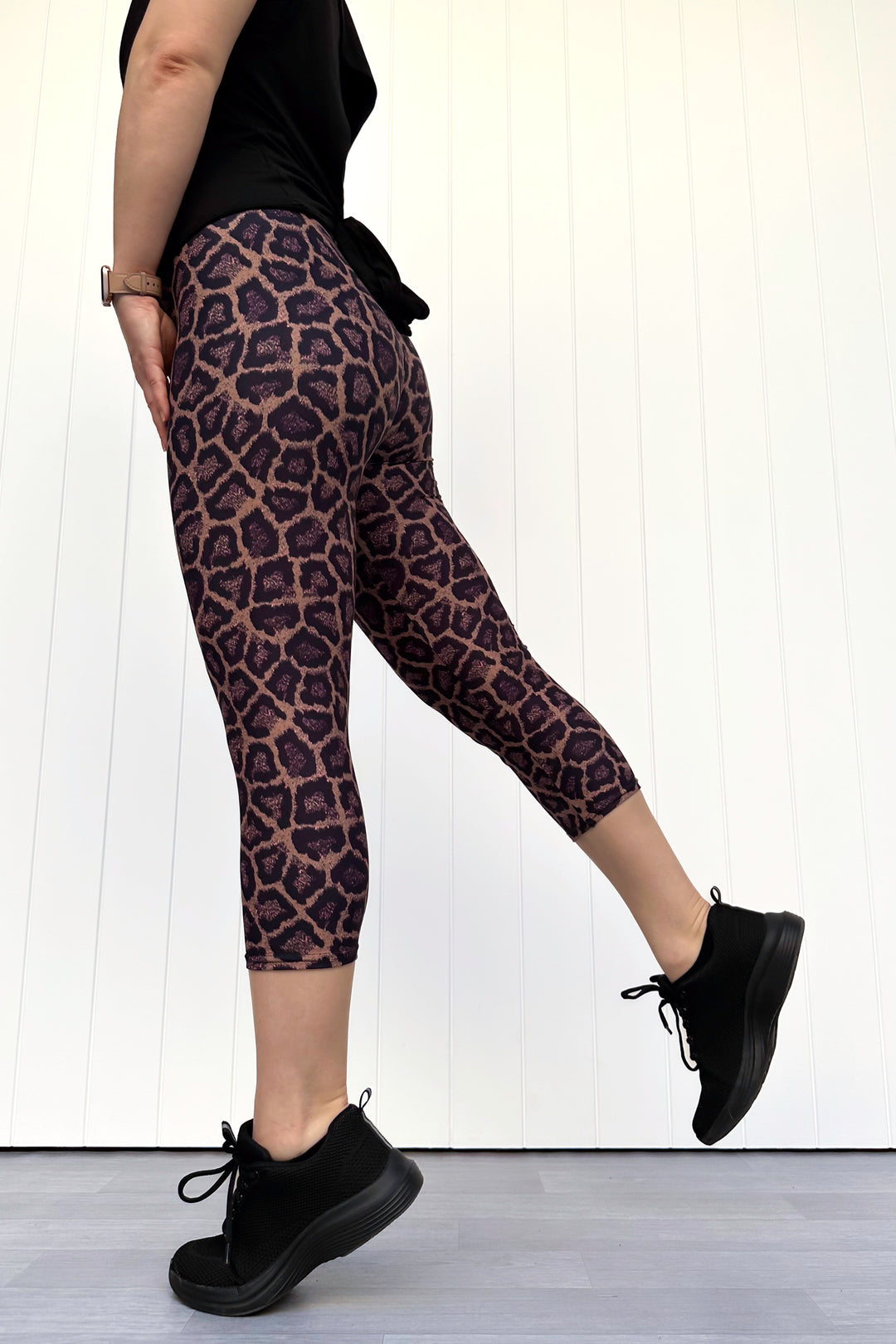 Person wearing leopard print leggings and black shoes on a white background