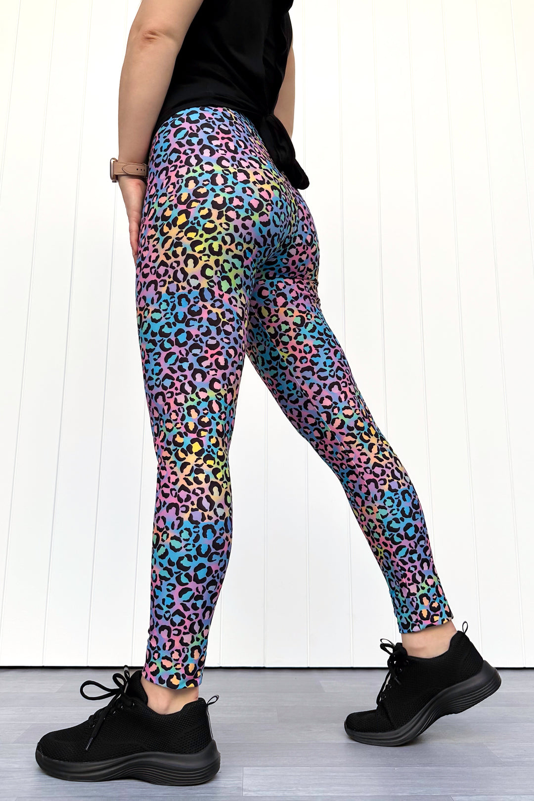 Person wearing colorful leopard print leggings with a white background