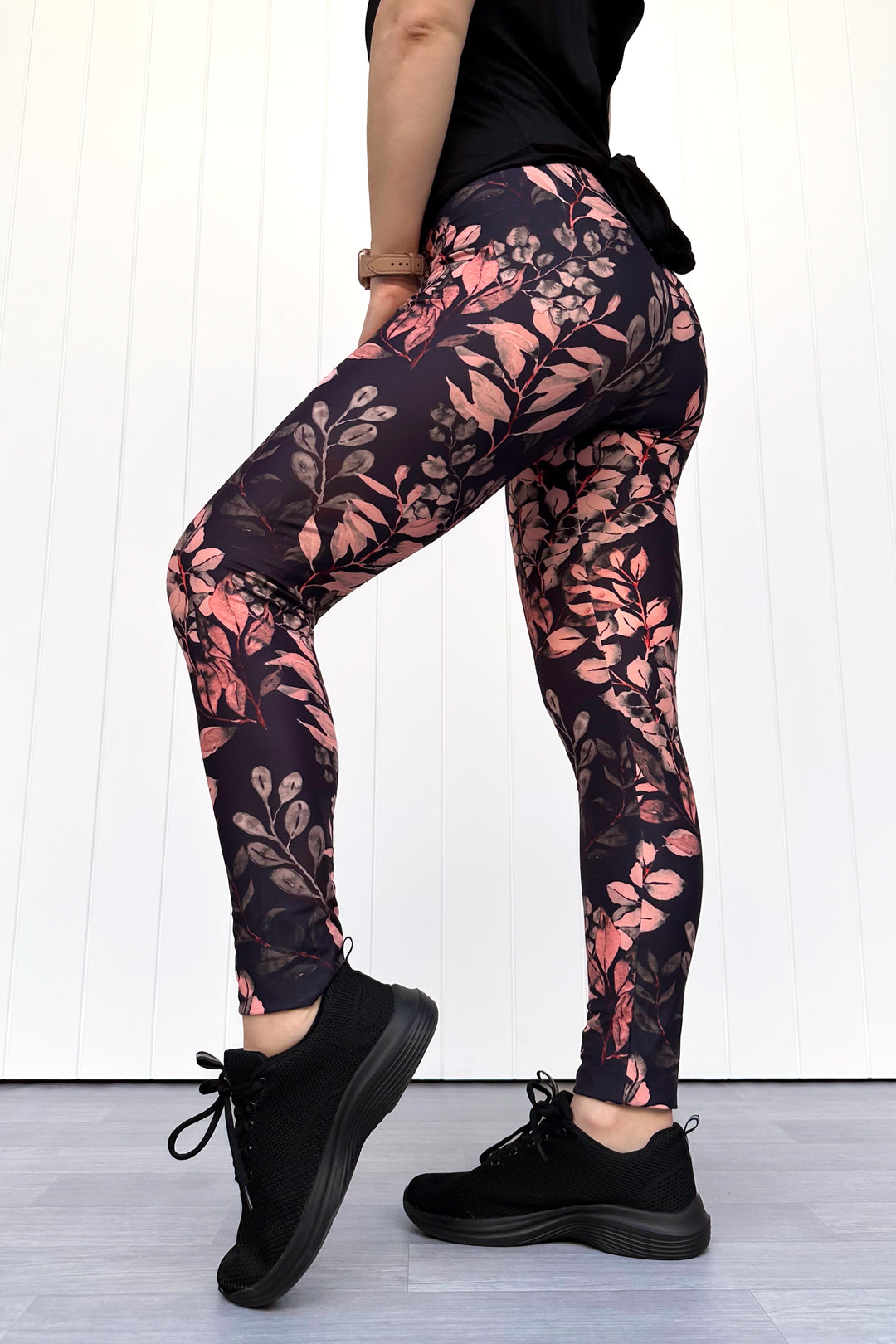 Person wearing black leggings with floral pattern against a white background