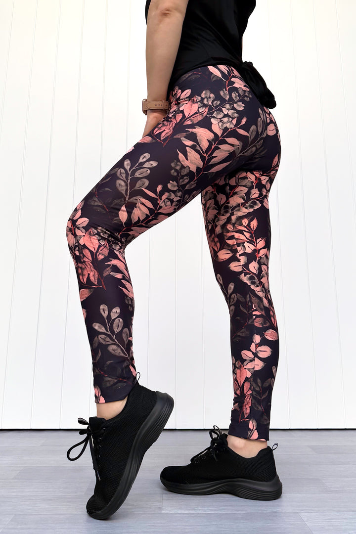 Person wearing black leggings with floral pattern against a white background