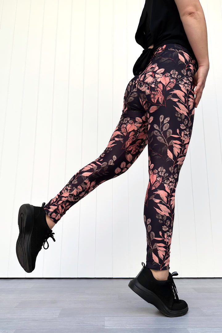 Person wearing black leggings with floral pattern against a white background