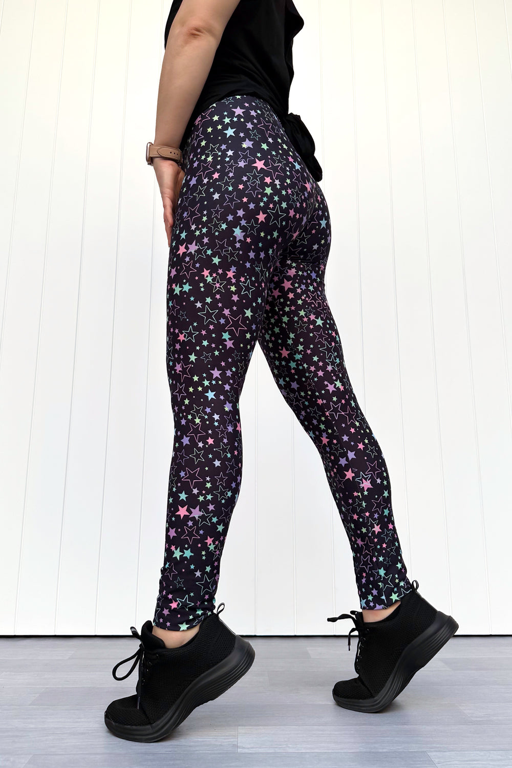 Person wearing black leggings with star pattern on a white background