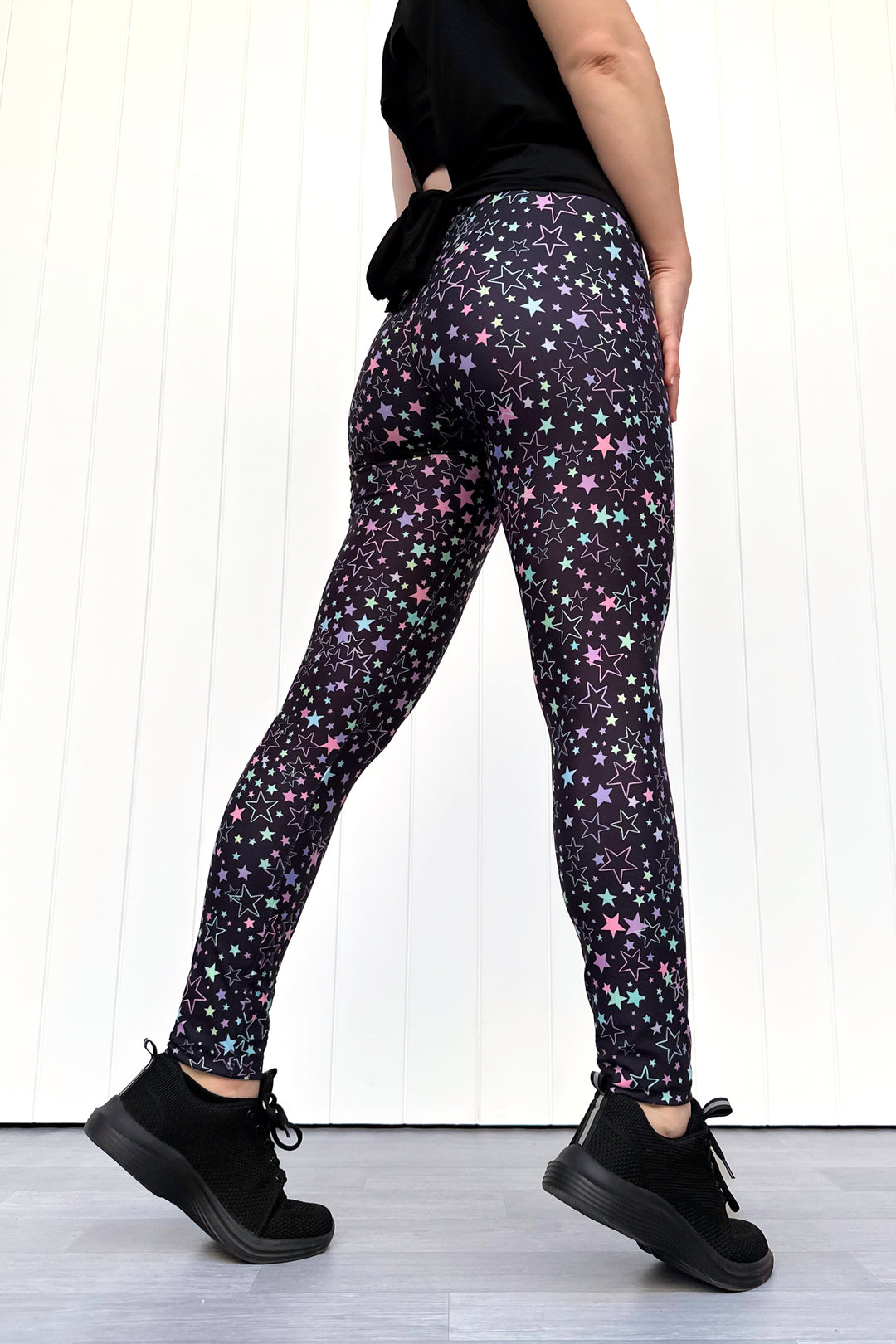 Person wearing black leggings with star pattern against a white background