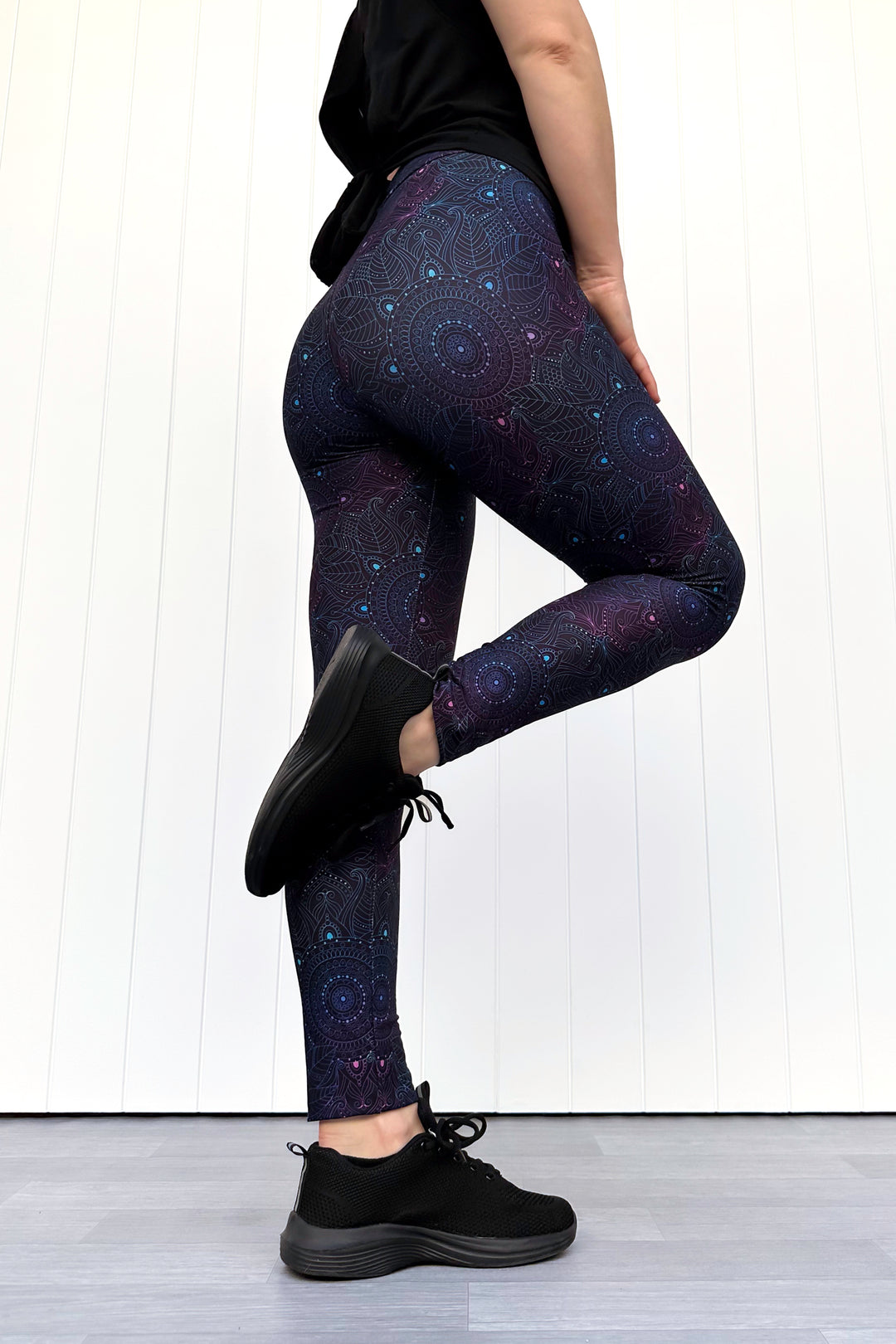 Person wearing dark purple leggings with a mandala pattern against a white background