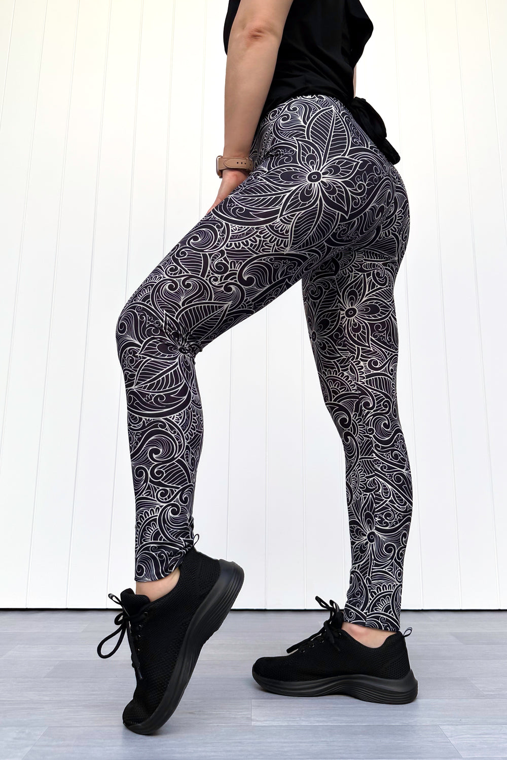Person wearing black and white patterned leggings with a white background