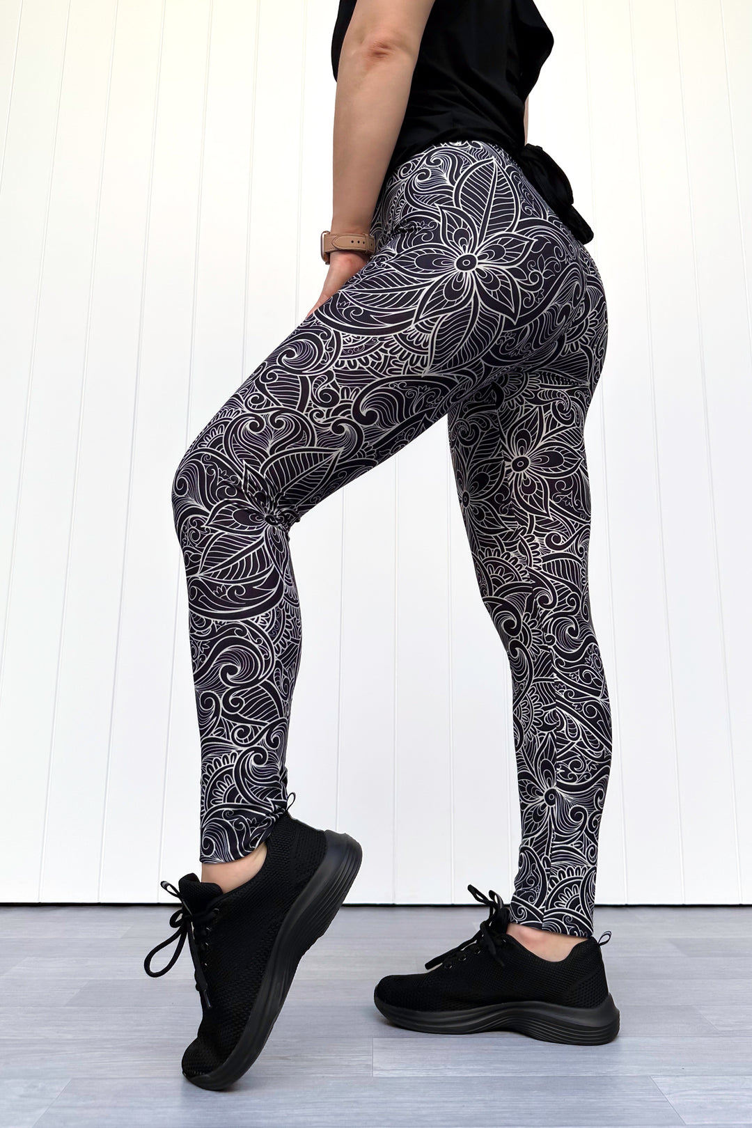 Person wearing black and white patterned leggings with a white background