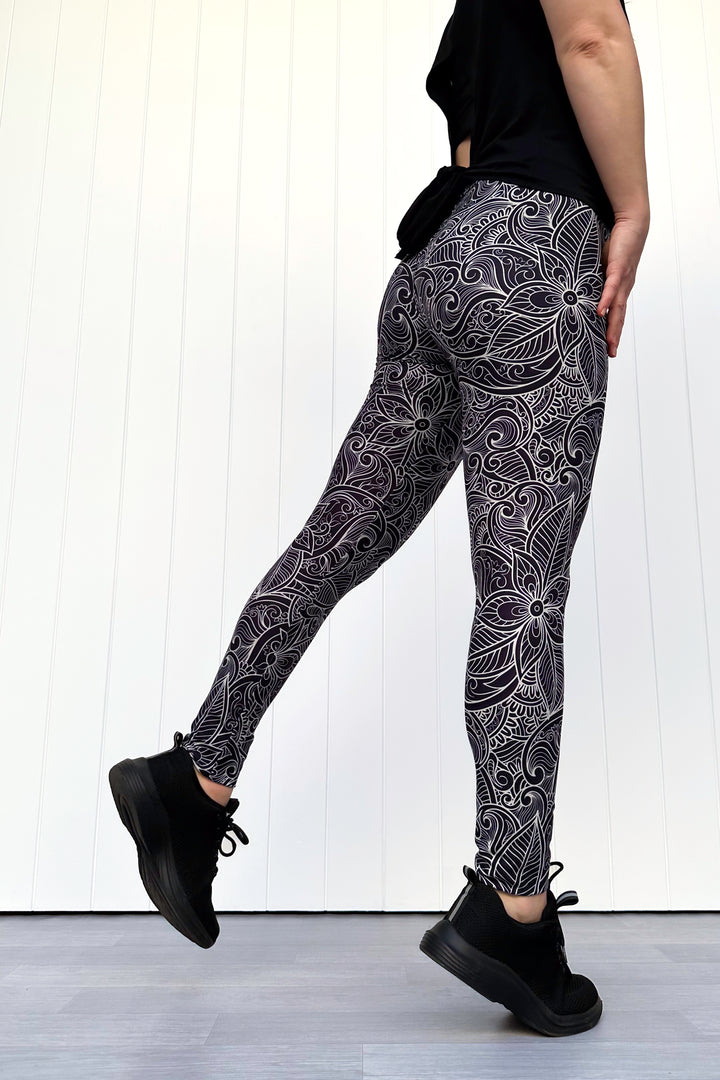 Person wearing black and white patterned leggings with a plain background