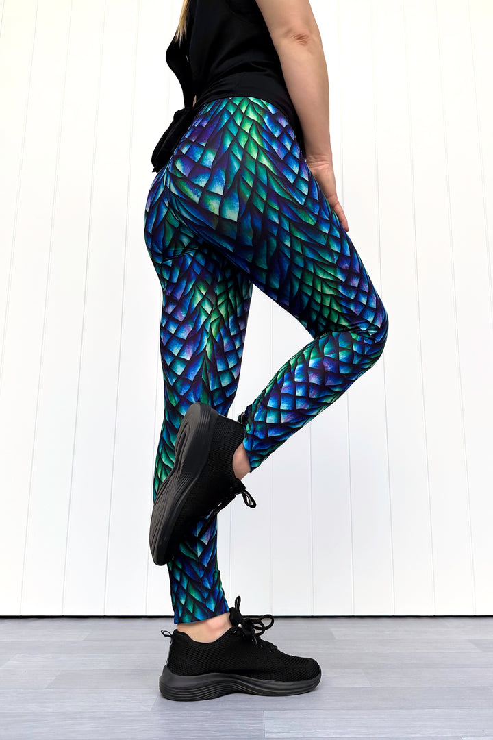 Person wearing leggings with a dragon scale pattern on a white background