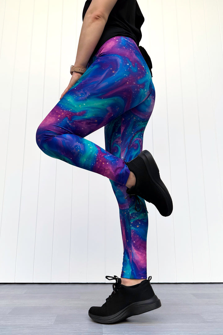 Person wearing galaxy-themed leggings on a white wooden floor.