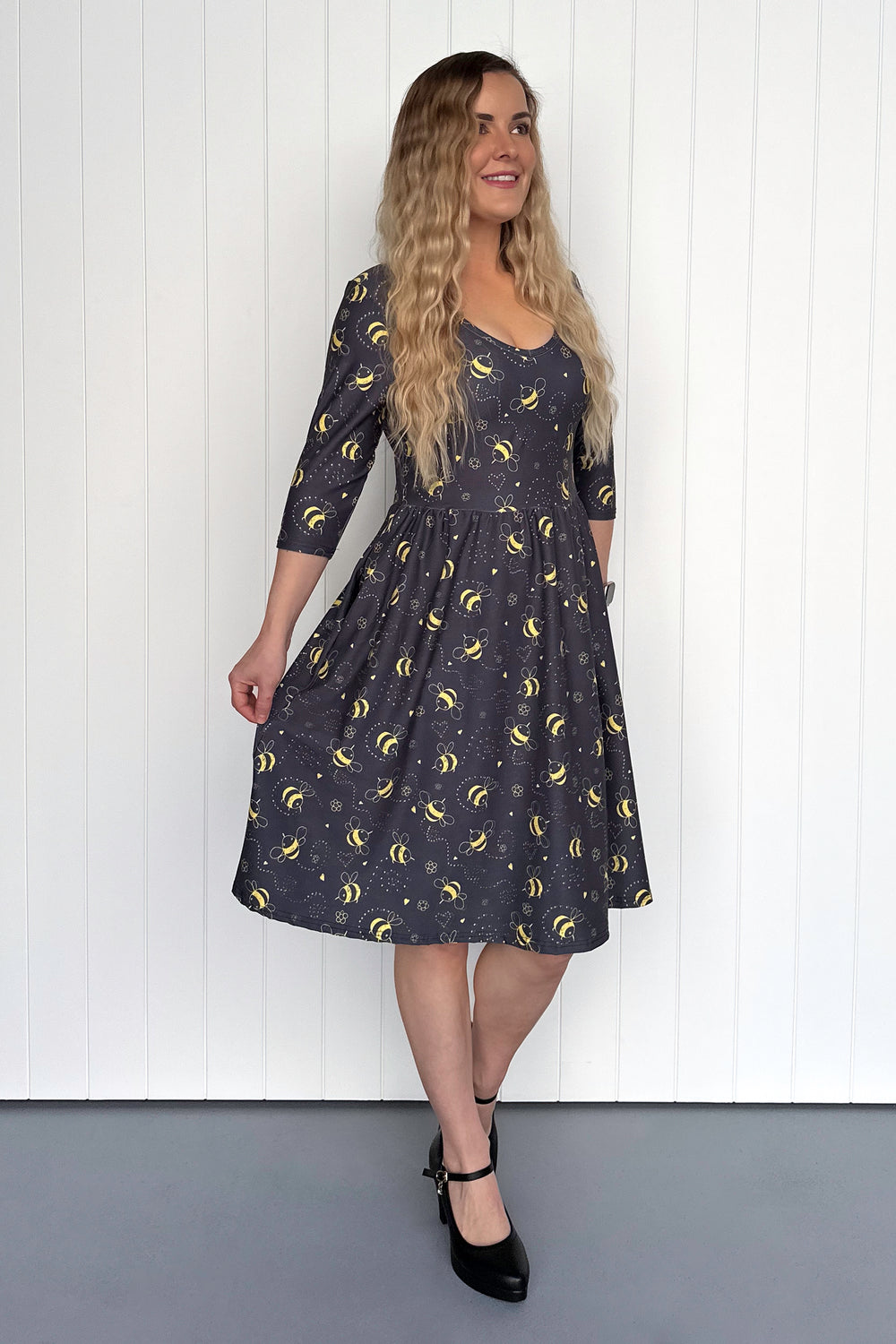 Woman wearing a black dress with yellow patterns against a white background